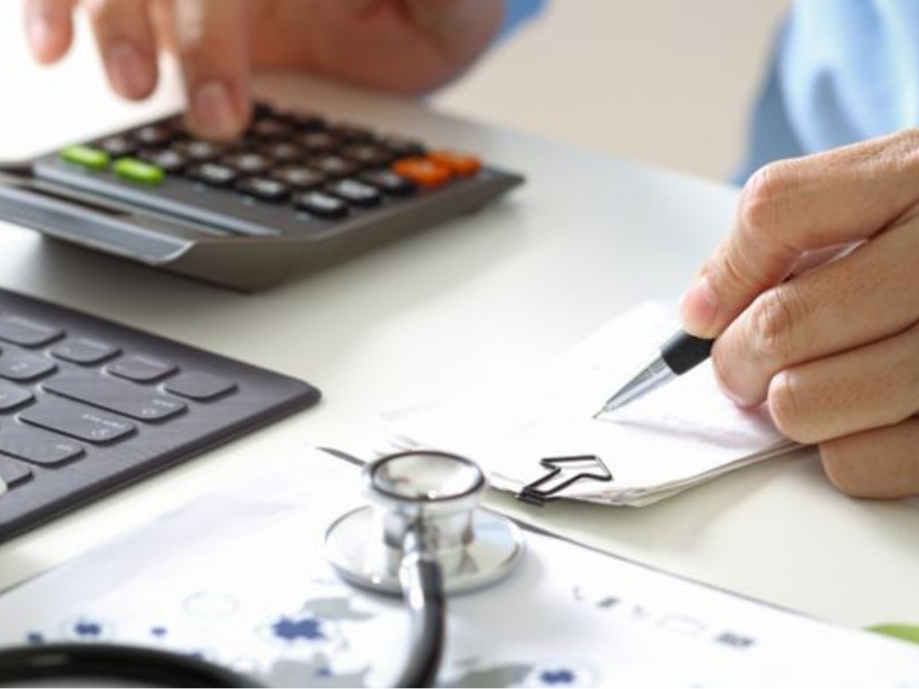 medico con calculadora y receta medica, representa los aumentos en prepagas agosto