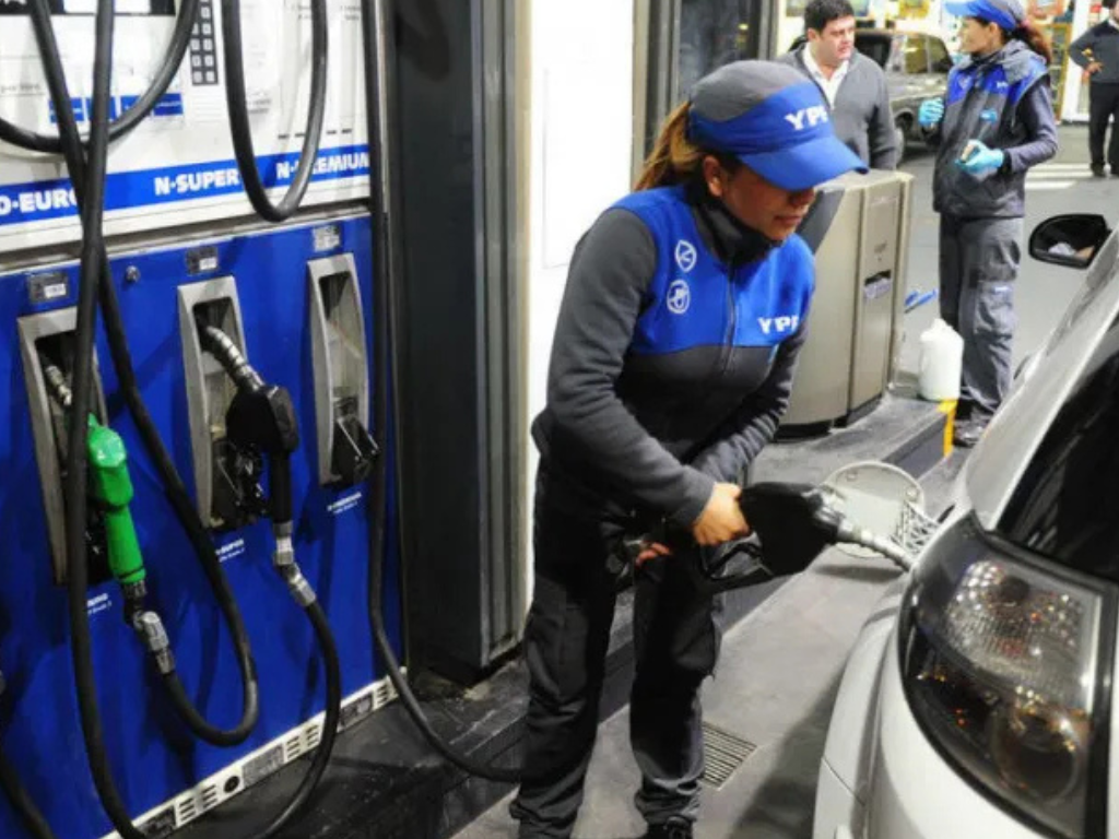 Persona cargando combustible en estación de servicio, símbolo del aumento de combustibles.