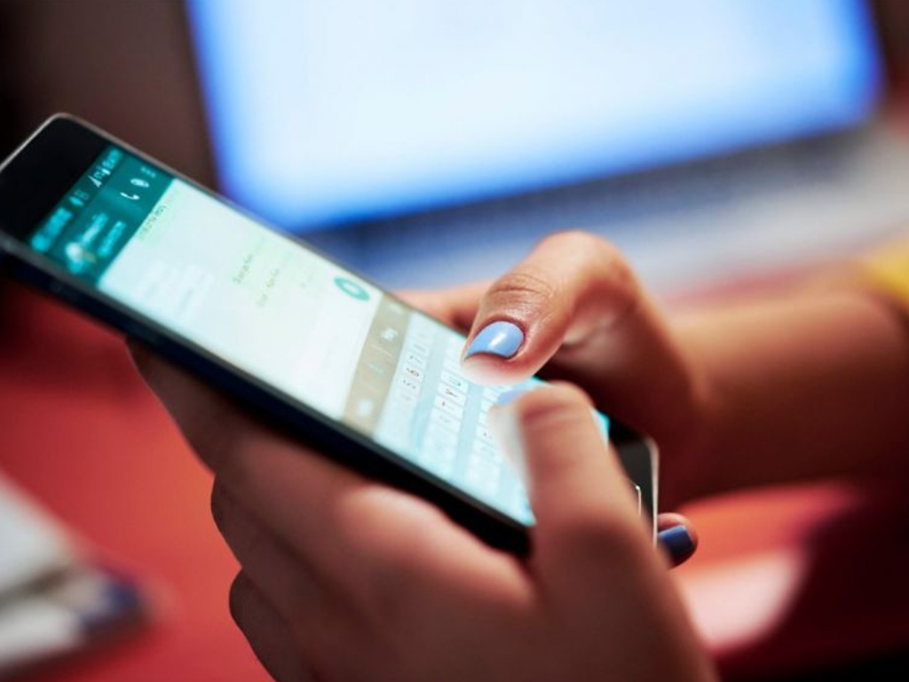 Mujer sosteniendo un celular, símbolo de la estafa familiar por créditos fraudulentos.