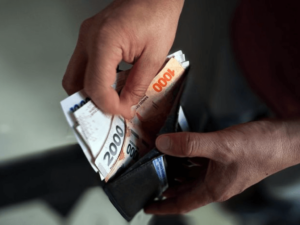 Manos abriendo una billetera con billetes de pesos argentinos para ilustrar la Inflación Argentina 2026.