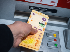 Persona retirando dinero de un cajero para el pago de trabajadores públicos.