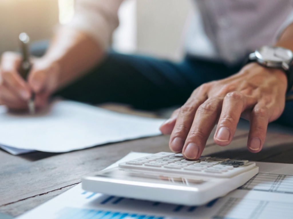 Hombre analizando papeles y usando una calculadora para cumplir con el plazo para recategorizarse en el Monotributo de ARCA.