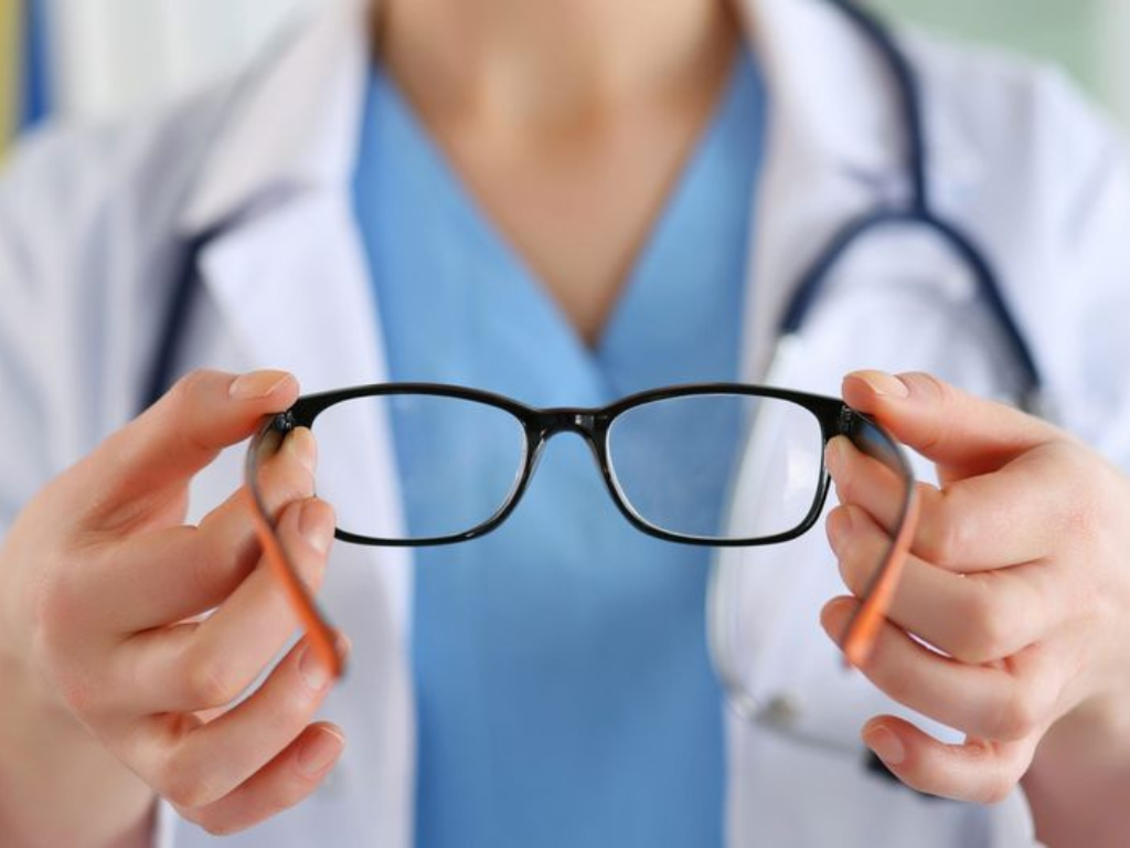 Profesional de salud sosteniendo anteojos, representando la auditoría de PAMI por fraude en prestaciones oftalmológicas.