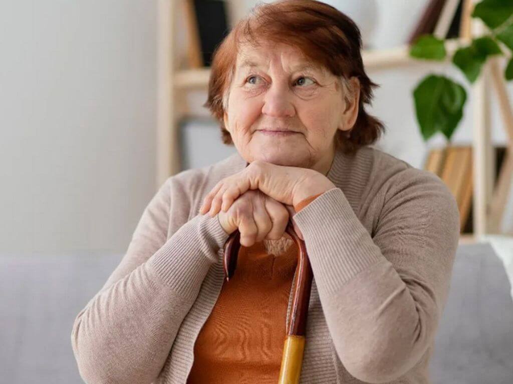 Una mujer jubilada sentada con su bastón esperando el cronograma de pagos de las PNC de mayo 2026.