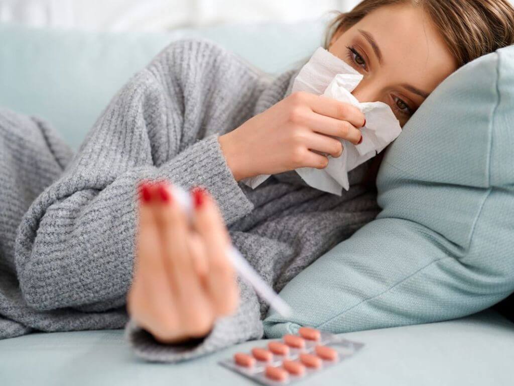 Una joven con fiebre se suena la nariz con un pañuelo, representando el aumento de casos de Gripe A en la provincia de Santa Fe.