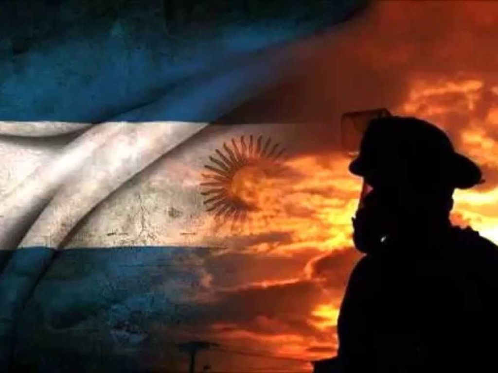 Bombero voluntario con equipo de protección y bandera argentina, en conmemoración del Día Nacional del Bombero Voluntario.
